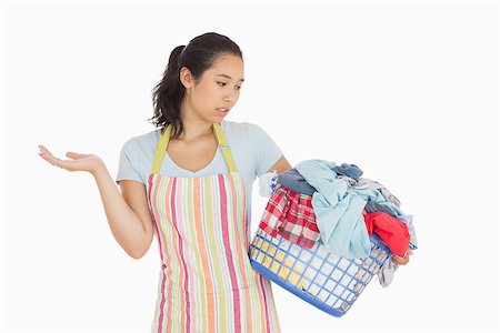 Quizzical looking young woman in apron looking at basket full of dirty laundry Stock Photo - Budget Royalty-Free & Subscription, Code: 400-06863717