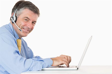 Smiling man with headphones typing on his laptop on his desk Stock Photo - Budget Royalty-Free & Subscription, Code: 400-06863798
