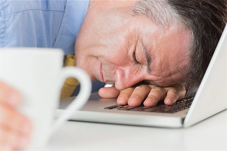 executive sleeping desk - Businessman holding coffee and sleeping on his laptop on his desk Stock Photo - Budget Royalty-Free & Subscription, Code: 400-06863791