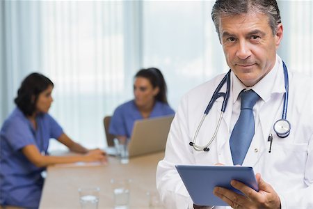 Smiling doctor with tablet at a meeting Stock Photo - Budget Royalty-Free & Subscription, Code: 400-06874041