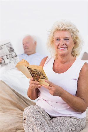 simsearch:400-06888132,k - Smiling aged couple reading book and newspaper in the bedroom Photographie de stock - Aubaine LD & Abonnement, Code: 400-06874425
