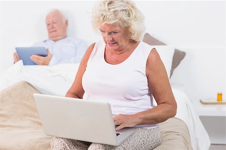 simsearch:400-06888132,k - Aged couple using a tablet and the laptop in the bedroom Photographie de stock - Aubaine LD & Abonnement, Code: 400-06874434