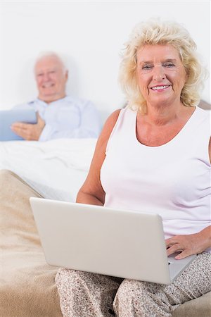 Happy aged couple using a tablet and the laptop in the bedroom Stock Photo - Budget Royalty-Free & Subscription, Code: 400-06874436