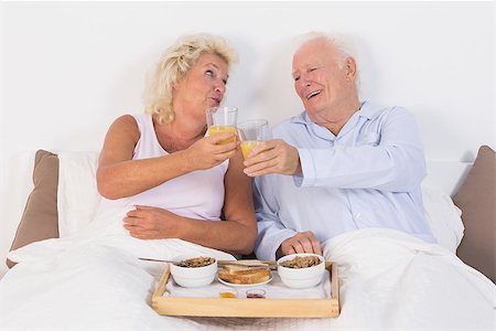 simsearch:400-06888132,k - Aged couple toasting with orange juice and lying on the bed Photographie de stock - Aubaine LD & Abonnement, Code: 400-06874451