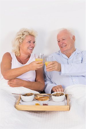 simsearch:400-06888132,k - Old couple toasting at breakfast with orange juice and lying on the bed Photographie de stock - Aubaine LD & Abonnement, Code: 400-06874452