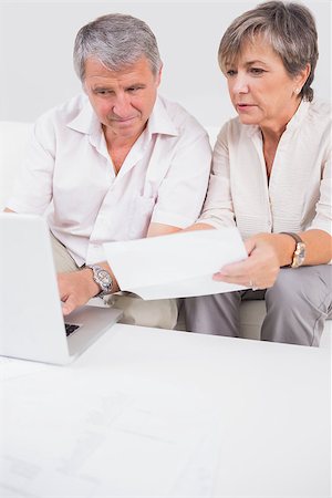 simsearch:400-06874653,k - Old lovers not understanding the accounts and using laptop in sitting room Photographie de stock - Aubaine LD & Abonnement, Code: 400-06874621