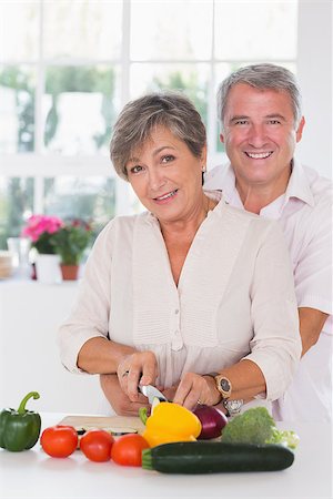 simsearch:400-06874653,k - Portrait of a woman cutting vegetables with her ??husband behind herin kitchen Photographie de stock - Aubaine LD & Abonnement, Code: 400-06874649