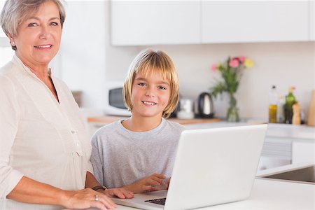 simsearch:400-06874653,k - Grandmother and child looking at the camera with a laptop in kitchen Photographie de stock - Aubaine LD & Abonnement, Code: 400-06874676