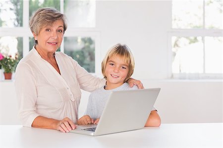 simsearch:400-06874653,k - Granny and child looking camera with a laptop in kitchen Photographie de stock - Aubaine LD & Abonnement, Code: 400-06874678