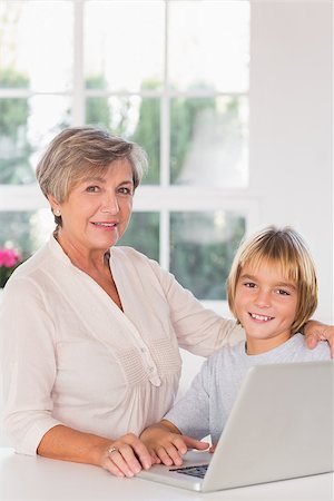 simsearch:400-06874653,k - Grandmother and child looking camera with a laptop in kitchen Photographie de stock - Aubaine LD & Abonnement, Code: 400-06874679