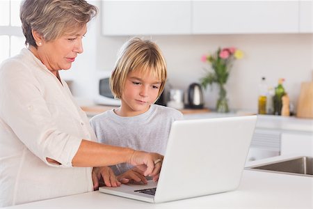 simsearch:400-06874653,k - Grandmother showing laptop to a child in kitchen Photographie de stock - Aubaine LD & Abonnement, Code: 400-06874672