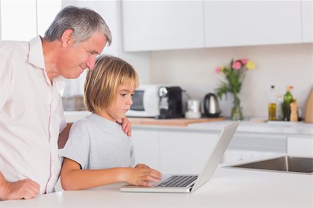 simsearch:400-06874653,k - Child and grandfather looking at laptop in kitchen Photographie de stock - Aubaine LD & Abonnement, Code: 400-06874684