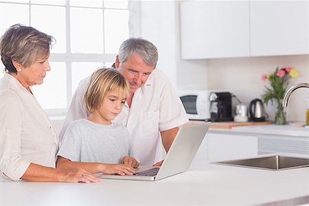 simsearch:400-06874653,k - Child and grandparents looking at laptop in kitchen Photographie de stock - Aubaine LD & Abonnement, Code: 400-06874680