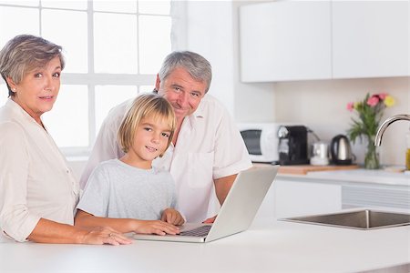 simsearch:400-06874610,k - Child and grandparents looking at camera with a laptop in kitchen Foto de stock - Super Valor sin royalties y Suscripción, Código: 400-06874681