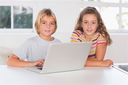 Two children looking at the camera with laptop in kitchen Stock Photo - Budget Royalty-Free & Subscription, Code: 400-06874697