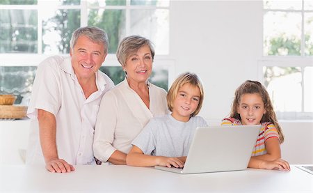 Children and grandparents looking at the camera together with laptop in front in kitchen Stock Photo - Budget Royalty-Free & Subscription, Code: 400-06874692