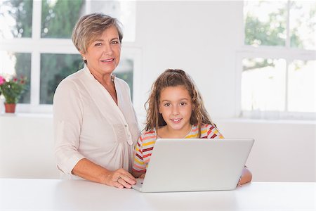 simsearch:400-06874653,k - Grandmother and child looking at camera together with laptop in kitchen Photographie de stock - Aubaine LD & Abonnement, Code: 400-06874704