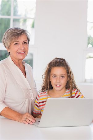 simsearch:400-06874653,k - Smiling grandmother and child looking at camera together with laptop in kitchen Photographie de stock - Aubaine LD & Abonnement, Code: 400-06874705