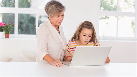 simsearch:400-06874653,k - Grandmother and child looking at laptop together in kitchen Photographie de stock - Aubaine LD & Abonnement, Code: 400-06874703