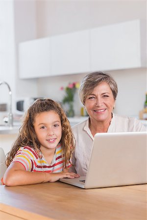 Smiling child and granny looking at the camera with laptop in kitchen Stock Photo - Budget Royalty-Free & Subscription, Code: 400-06874710