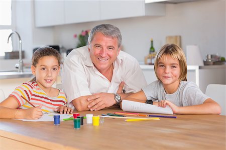 Grandfather and her grandchildren smiling at the camera with drawings in kitchen Stock Photo - Budget Royalty-Free & Subscription, Code: 400-06874720