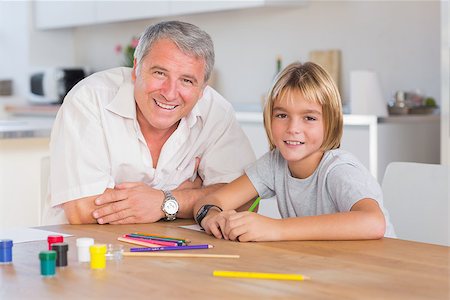 Grandfather and grandson looking at camera with drawings in kitchen Stock Photo - Budget Royalty-Free & Subscription, Code: 400-06874722