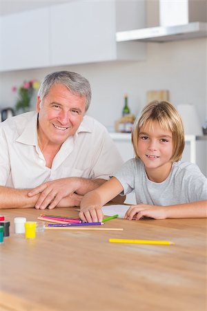 Grandson and grandfather looking at camera with drawings in kitchen Stock Photo - Budget Royalty-Free & Subscription, Code: 400-06874723