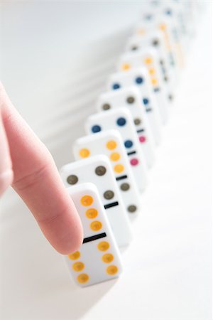 Finger about to knock over line of colourful dominoes on white background Stock Photo - Budget Royalty-Free & Subscription, Code: 400-06875641