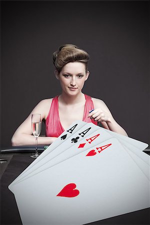 Attractive gambler betting on hand of four aces in the foreground Stock Photo - Budget Royalty-Free & Subscription, Code: 400-06875665