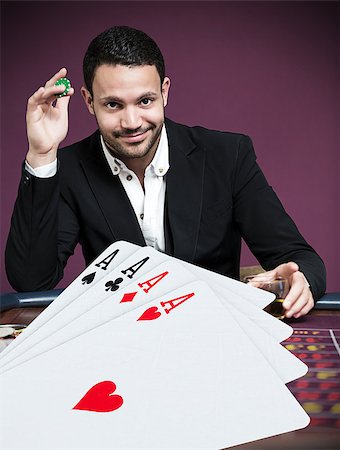 Handsome gambler betting on four aces in foreground Stock Photo - Budget Royalty-Free & Subscription, Code: 400-06875667