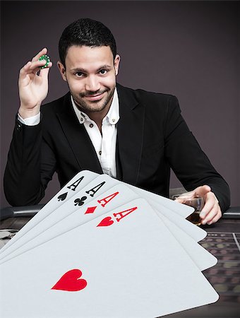 Handsome gambler betting on four digital aces at poker table Stock Photo - Budget Royalty-Free & Subscription, Code: 400-06875668