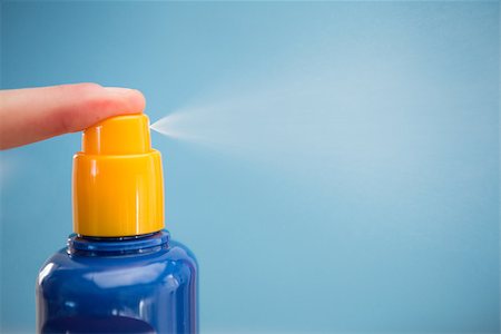 Finger spraying sun tan lotion with copy space on blue background Stock Photo - Budget Royalty-Free & Subscription, Code: 400-06876243