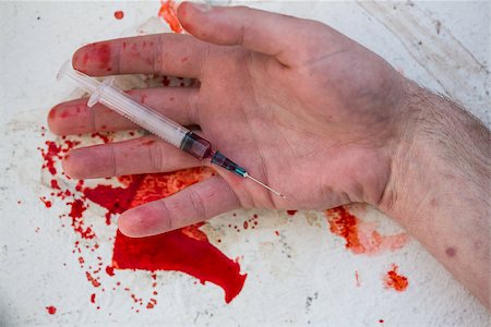 Lifeless hand holding bloody syringe in pool of blood Stock Photo - Budget Royalty-Free & Subscription, Code: 400-06876266
