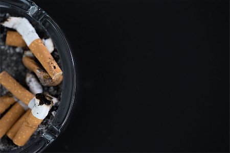 simsearch:400-06876304,k - Ashtray full of butts with copy space on black background Stock Photo - Budget Royalty-Free & Subscription, Code: 400-06876308