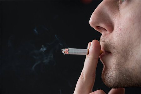 simsearch:400-06876304,k - Man smoking cigarette on black background Stockbilder - Microstock & Abonnement, Bildnummer: 400-06876302
