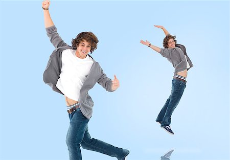 Two of the same teenage boy jumping for joy on blue background Stock Photo - Budget Royalty-Free & Subscription, Code: 400-06877088
