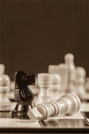 simsearch:400-06876600,k - Fallen white chess piece lying next to black knight on board in sepia tone Stock Photo - Budget Royalty-Free & Subscription, Code: 400-06877140