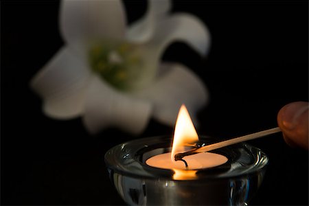 simsearch:400-09050035,k - Hand lighting tea light candle with white lily in background symbolising loss Stock Photo - Budget Royalty-Free & Subscription, Code: 400-06877259