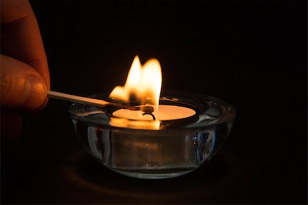 Hand lighting tea light candle in glass holder in the dark Foto de stock - Super Valor sin royalties y Suscripción, Código: 400-06877261