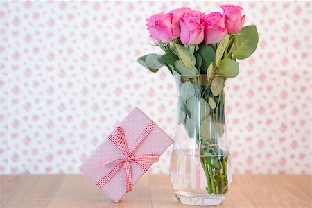 simsearch:400-06877945,k - Bouquet of pink roses in vase with pink gift leaning against it on wooden table Stock Photo - Budget Royalty-Free & Subscription, Code: 400-06877344