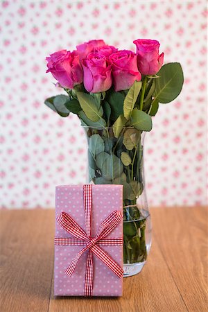 simsearch:400-06877837,k - Bunch of pink roses in vase with pink gift leaning against it on wooden table Stock Photo - Budget Royalty-Free & Subscription, Code: 400-06877347
