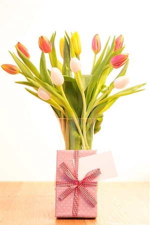 simsearch:400-06877837,k - Vase of pink white and yellow tulips on wooden table with gift and blank card Stock Photo - Budget Royalty-Free & Subscription, Code: 400-06877370