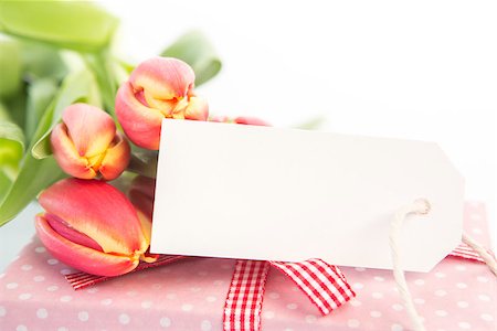 simsearch:400-06877837,k - Bouquet of beautiful tulips next to a gift with an empty card on a white table Stock Photo - Budget Royalty-Free & Subscription, Code: 400-06877851