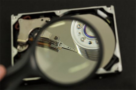 Hand holding magnifying glass over disk drive on black background Photographie de stock - Aubaine LD & Abonnement, Code: 400-06878348