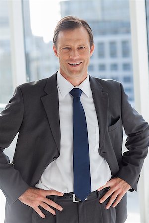 simsearch:400-06879262,k - Smiling businessman with his hands on hips in his office Stock Photo - Budget Royalty-Free & Subscription, Code: 400-06879260