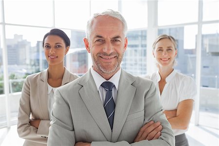 simsearch:400-06879270,k - Smiling businessman standing in front of colleagues with arms folded Stock Photo - Budget Royalty-Free & Subscription, Code: 400-06879291