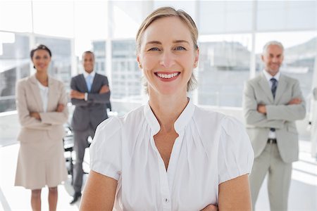 simsearch:400-06879270,k - Cheerful businesswoman standing with arms folded in front of colleagues Stock Photo - Budget Royalty-Free & Subscription, Code: 400-06879328