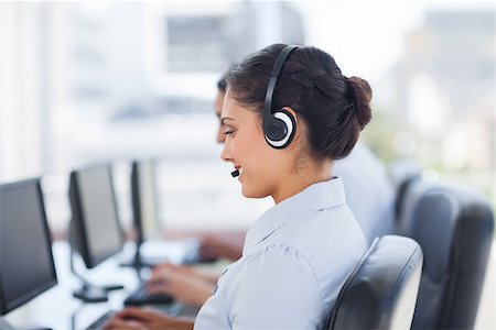 Attractive brunette working in a call centre with her headset Foto de stock - Super Valor sin royalties y Suscripción, Código: 400-06879369