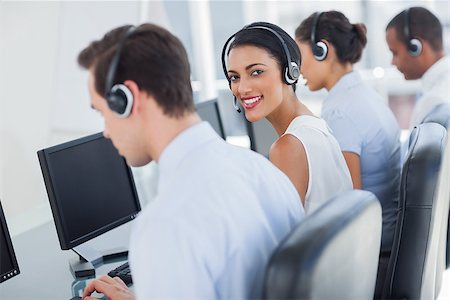 Smiling call centre employee looking over shoulder while having a discussion Stock Photo - Budget Royalty-Free & Subscription, Code: 400-06879384