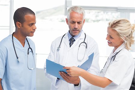 examination folder - Three serious doctors examining a file in a bright office Stock Photo - Budget Royalty-Free & Subscription, Code: 400-06879474
